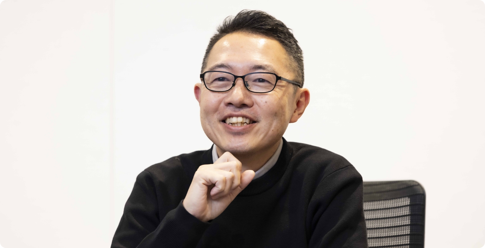 男性が顎に手をあててインタビューに答えている写真